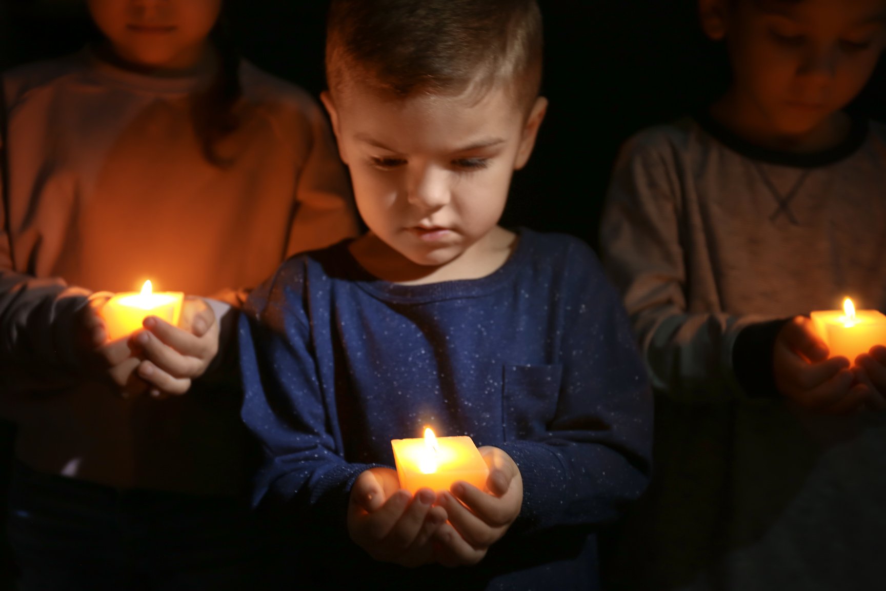 Little Children Holding Burning Candles in Darkness